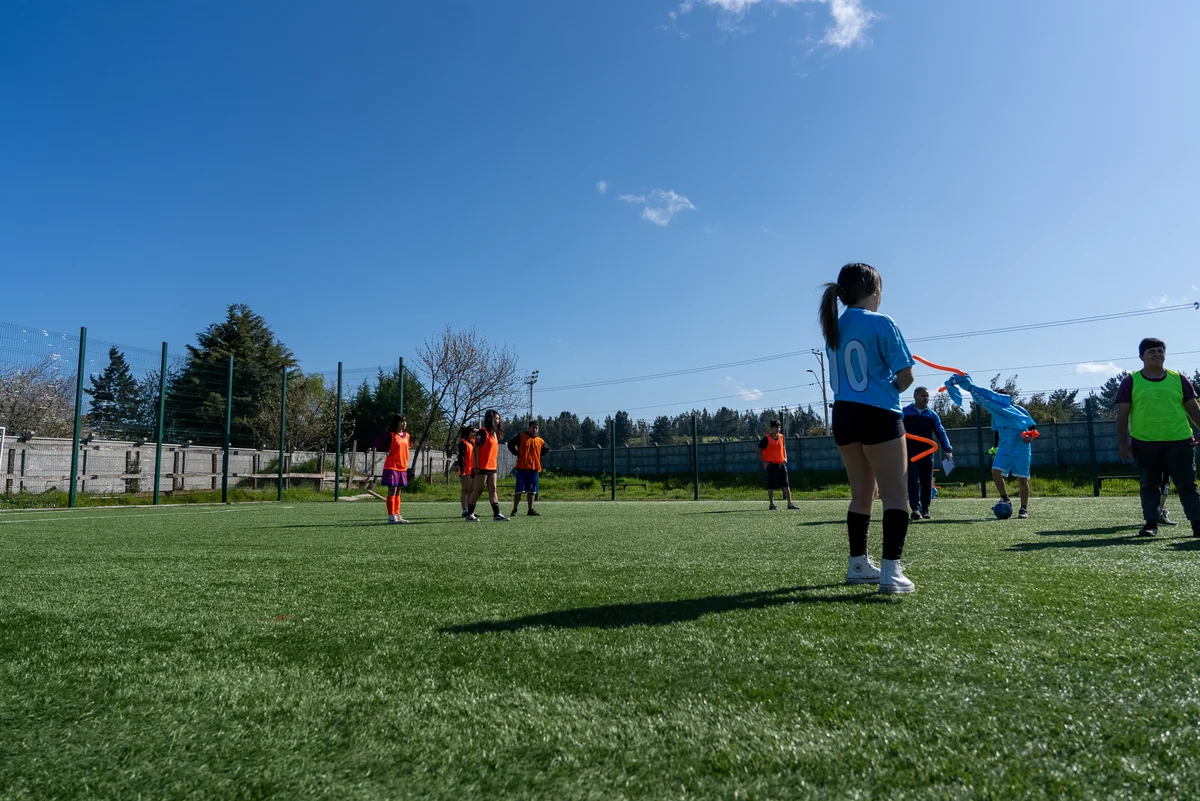 Estudiantes en una actividad deportiva en la cancha de baby fútbol con pasto sintético